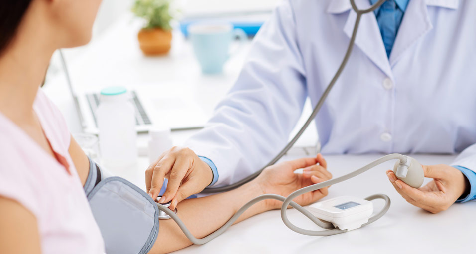 Frau beim Blutdruckmessen als Beispiel für Herzinsuffizienz-Ursachen